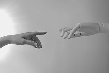 Black and white of a human and robotic hand reaching towards each other, symbolizing connection. HD wallpaper
