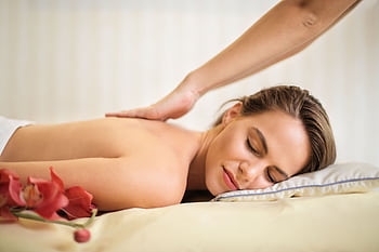 A serene spa scene featuring a woman receiving a therapeutic massage, surrounded by soothing elements. HD wallpaper