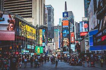 Bustling daytime view of Times Square with crowds, skyscrapers, and iconic billboards in New York City. HD wallpaper