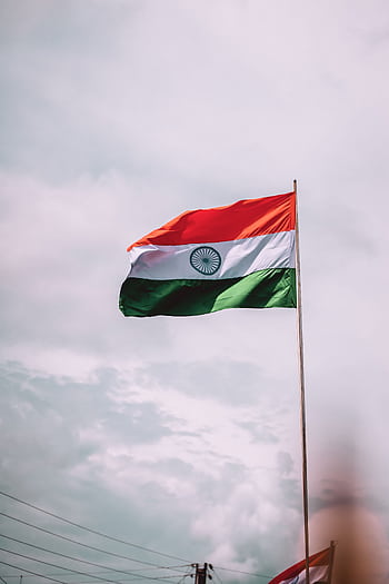 Indian national flag flying high with a cloudy sky backdrop symbolizing pride and patriotism. HD phone wallpaper