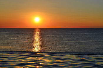 A breathtaking sunset over the ocean, reflecting vibrant hues of orange and yellow. HD wallpaper