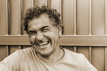 Close-up sepia portrait of a happy, laughing man against a textured background. HD wallpaper