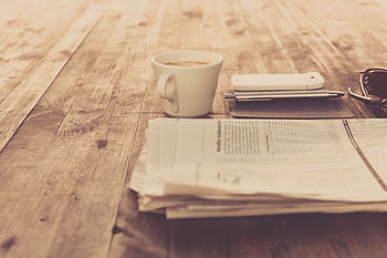 A warm vintage morning setup with coffee, newspaper, and smart on wooden table. HD wallpaper