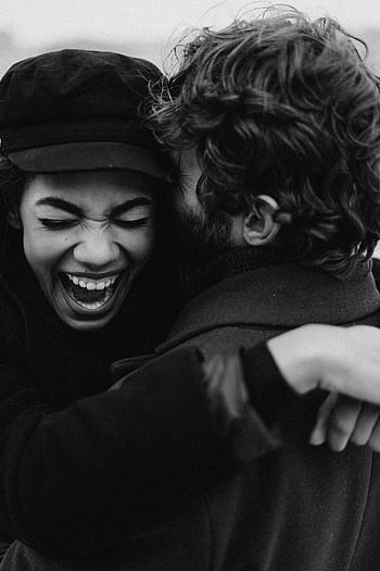 Monochrome of a joyful couple embracing with laughter and happiness outdoors. HD phone wallpaper