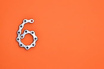 A creative display of a bike chain forming the number six against a vibrant orange backdrop. HD wallpaper