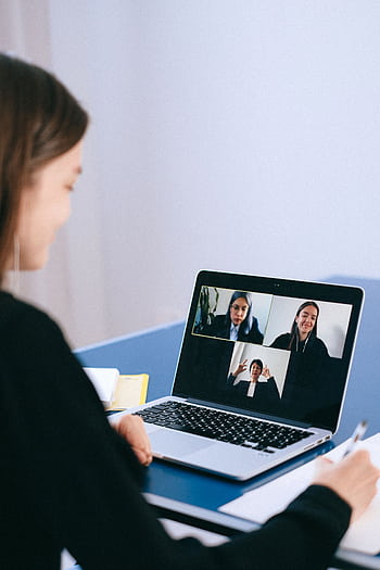 A woman participates in a virtual meeting with colleagues via video call on a laptop. HD phone wallpaper