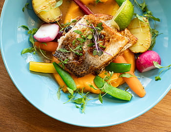 Colorful salmon dish with fresh vegetables on a blue plate, perfect for gourmet cuisine lovers. HD wallpaper