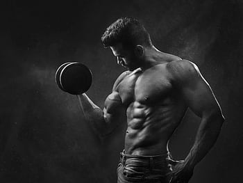 Powerful black and white portrait of a shirtless bodybuilder lifting dumbbells in the gym. HD wallpaper