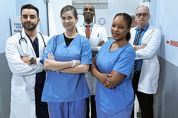 A diverse team of doctors and nurses smiling confidently in a hospital setting. HD wallpaper