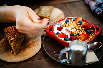 Close-up of a breakfast setting with granola, fresh berries, and a slice of cake. HD wallpaper