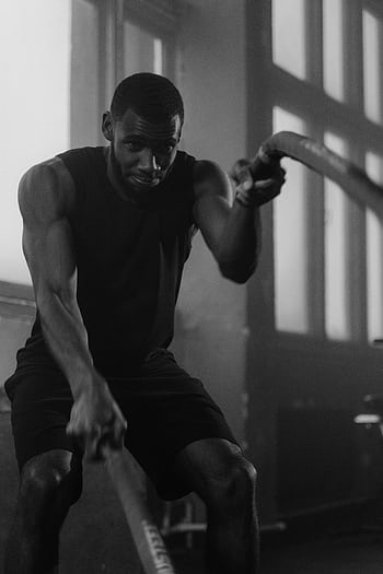 Focused man in gym intensively training with ropes indoors. HD phone wallpaper