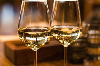 Two elegant wine glasses filled with white wine, captured with a beautiful bokeh effect. HD wallpaper