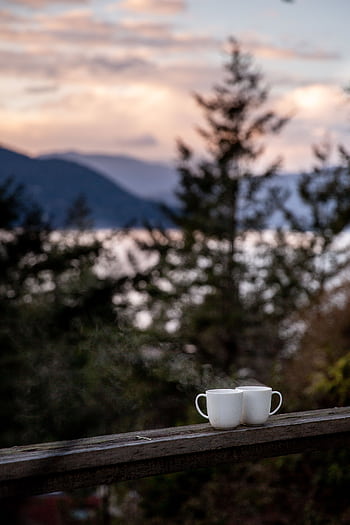 Serene landscape view with two coffee mugs on a wooden railing at sunset. HD phone wallpaper