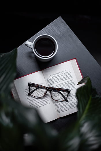 A serene setting with an open book, eyeglasses, and a steaming cup of coffee on a dark table. HD phone wallpaper