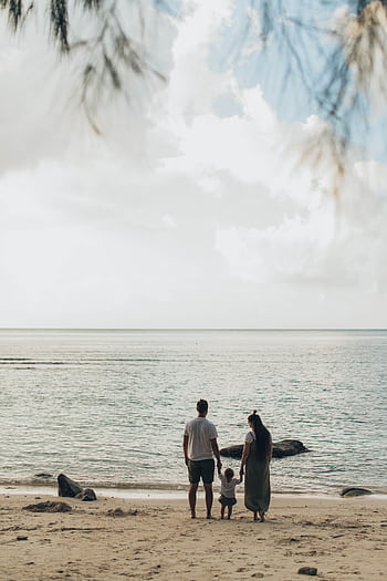 A family enjoys a tranquil day at the beach, highlighting togetherness and love. HD phone wallpaper