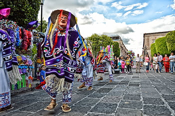 Colorful street parade in Mexico showcasing traditional costumes and cultural celebration. HD wallpaper