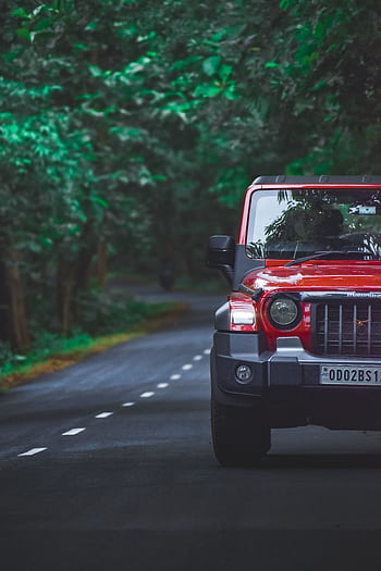 A red SUV navigates a winding road surrounded by lush green forest, capturing the essence of adventure and travel. HD phone wallpaper