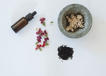 Flat lay of natural skincare ingredients including flowers, black seeds, and a dropper bottle. HD wallpaper