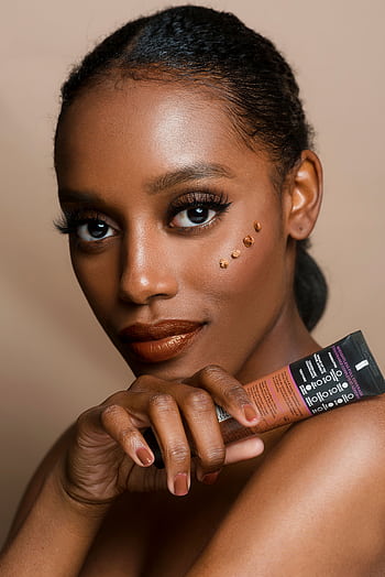Elegant portrait of a woman showcasing skincare product with flawless makeup and glowing skin. HD phone wallpaper