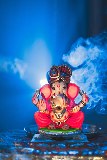 Traditional Ganesha statue with backlit smoke in a spiritual setting, Nanded, India. HD phone wallpaper