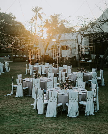 Charming sunset-lit outdoor wedding setup with adorned tables and chairs, perfect for celebrating love. HD phone wallpaper