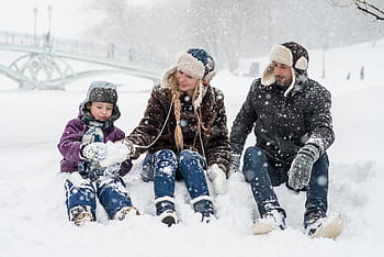 Happy family enjoying playful time in snowy winter park, capturing joyful moments in nature. HD wallpaper
