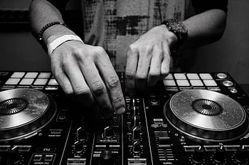 Close-up of a DJ's hands adjusting controls on a mixer in monochrome. HD wallpaper