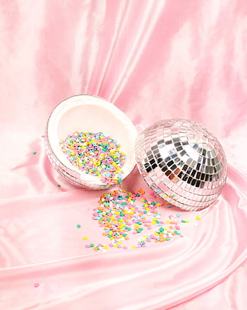Vibrant confetti spills from a disco ball on a soft pink satin backdrop. HD phone wallpaper