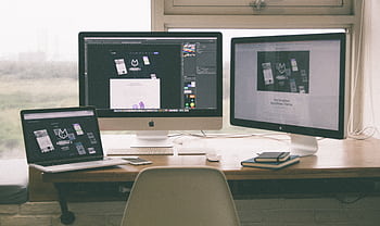Stylish and efficient workspace with multiple monitors, laptop, and smart, showcasing a web design project. HD wallpaper