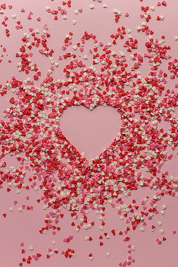 Heart-shaped confetti arrangement on a pink background, ideal for romantic and festive occasions. HD phone wallpaper