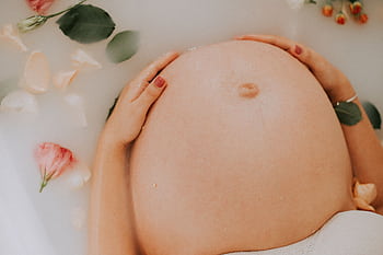 Pregnant woman relaxing in a soothing milk bath with flowers, embracing maternity. HD wallpaper
