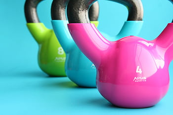 Vibrant colored kettlebells on blue background highlighting fitness and exercise equipment. HD wallpaper