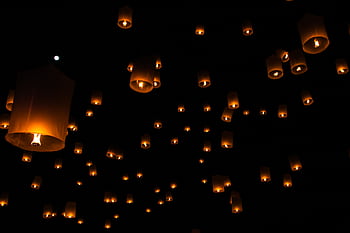 Sky lanterns float against a dark night sky during a traditional festival in Thailand. HD wallpaper