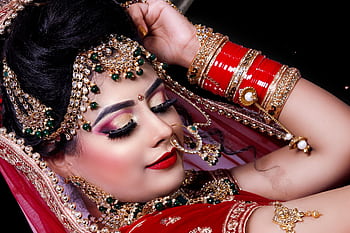 Close-up of an Indian bride showcasing ornate jewelry and vibrant traditional attire. HD wallpaper