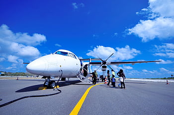 A group of people board a propeller airplane on a sunny day in Fuvahmulah, Maldives. HD wallpaper