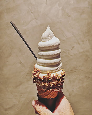 Close-up of a vanilla ice cream cone with textured waffle cone and nut toppings held by a hand. HD phone wallpaper