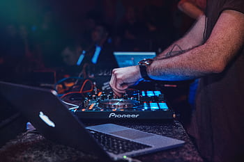 DJ performing with mixer in a vibrant nightclub setting. Perfect for entertainment and technology themes. HD wallpaper