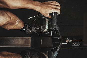 A close-up shot of a man using a rowing machine indoors, focusing on footwear and equipment. HD wallpaper