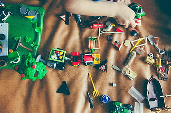 Children's hands playing with colorful toys on a mat, sparking creativity and fun. HD wallpaper