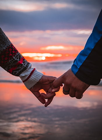 Close-up of a couple holding hands by the beach during a warm sunset. HD phone wallpaper