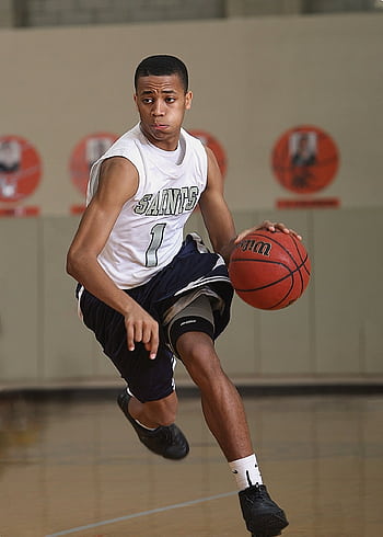 Energetic basketball player in mid-dribble on an indoor court. HD phone wallpaper