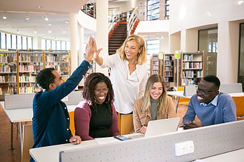 Cheerful diverse group of students collaborating in a library, celebrating with a high five. HD wallpaper