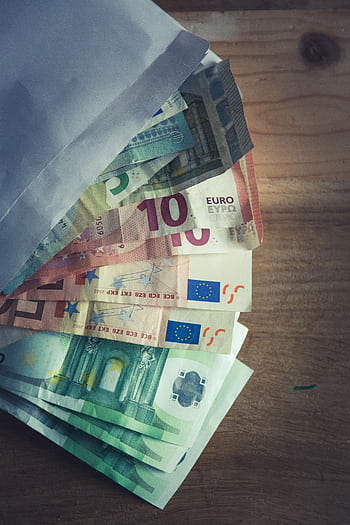 A collection of Euro banknotes emerging from an envelope on a wooden surface. HD phone wallpaper