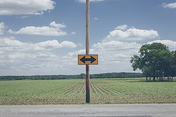 Scenic rural road sign on farmland with clear blue sky and clouds. HD wallpaper