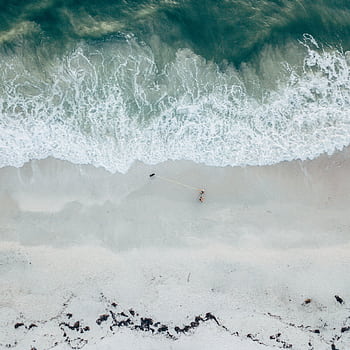 A tranquil aerial of a sandy beach with gentle waves, offering a peaceful seaside escape. HD phone wallpaper