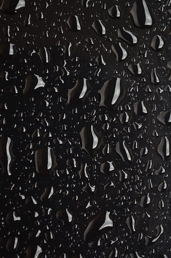 Macro shot of water droplets on a black surface, showcasing texture and detail. HD phone wallpaper