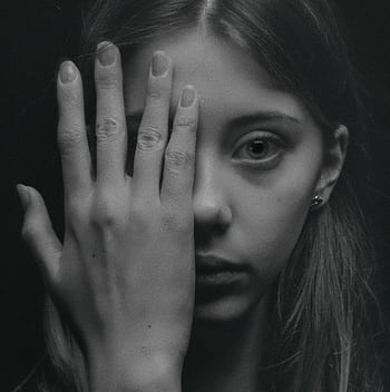 A striking black and white portrait of a young woman with a contemplative expression, shot in a studio. HD phone wallpaper