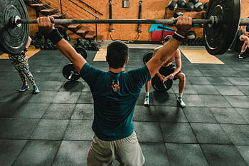 A group of men engaged in a vigorous weightlifting session at a gym. HD wallpaper