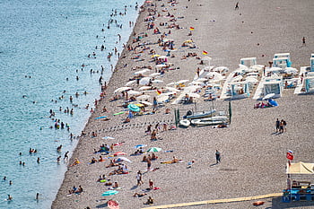 Crowded Antalya beach with sunbathers, umbrellas, and turquoise water, ideal summer destination. HD wallpaper