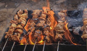 Juicy skewers of grilled meat sizzling over open flames, creating a tasty barbecue feel. HD wallpaper